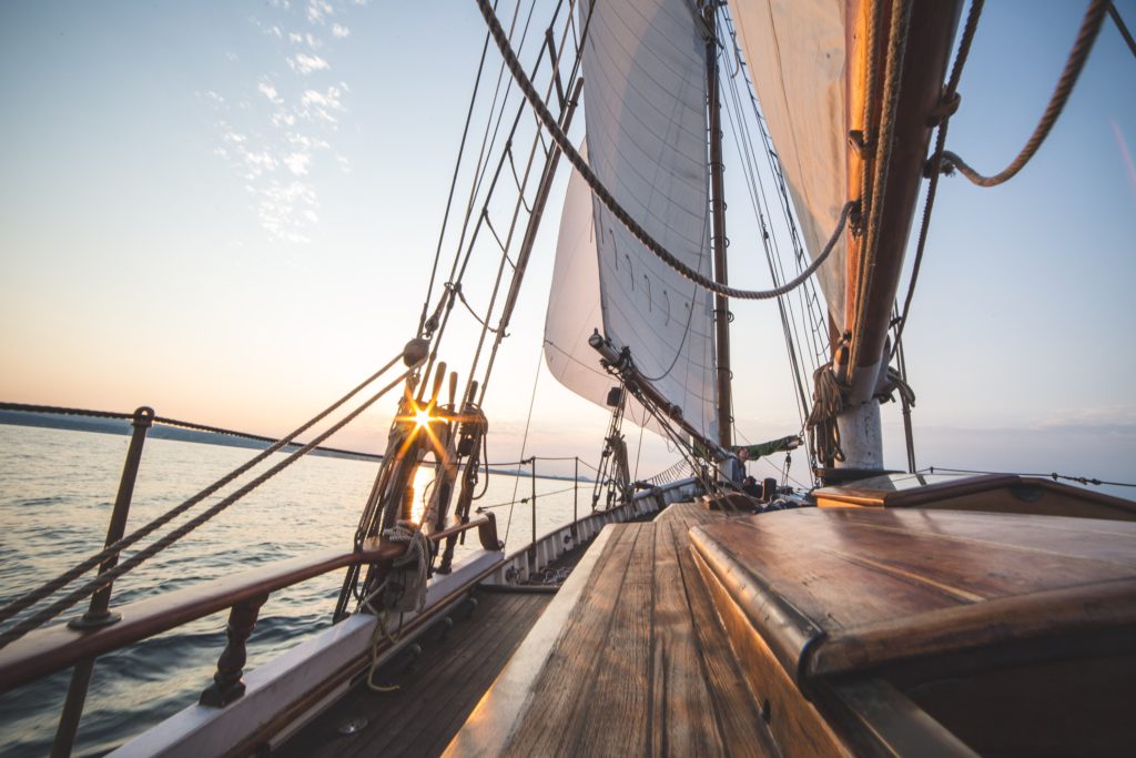 POV von einem Segelboot in Fahrrichtung. Sonnenuntergang am Horizont.