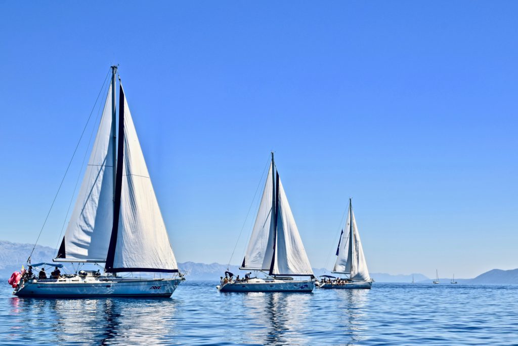 Drei weiße Segelboote auf dem Wasser mit blauem Himmel