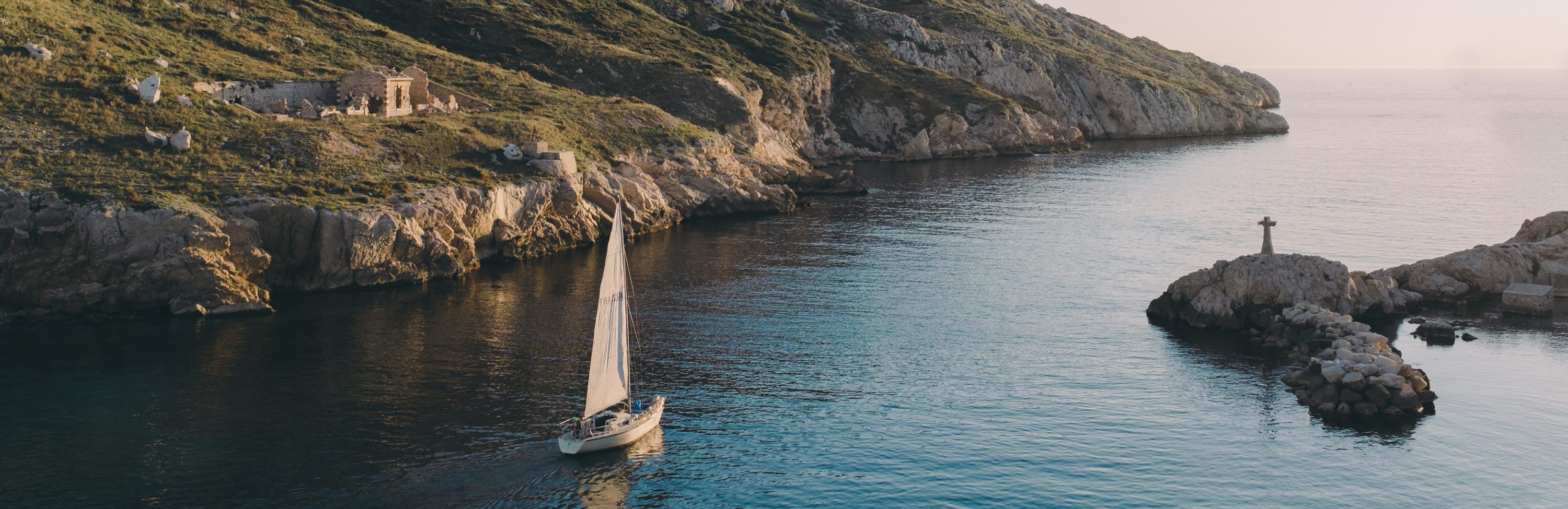 Segelkboot auf dem Wasser vor steiniger Küste